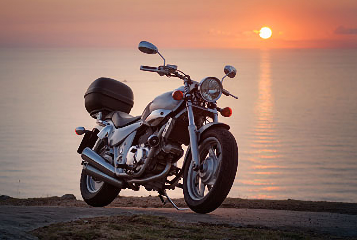 motorcycle parked by the seaside at sunset